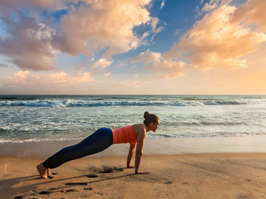 Woman doing Hatha yoga asana plank pose outdoors
