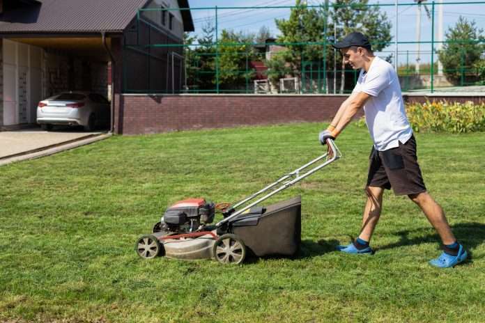 Man mowing the lawn in the backyard