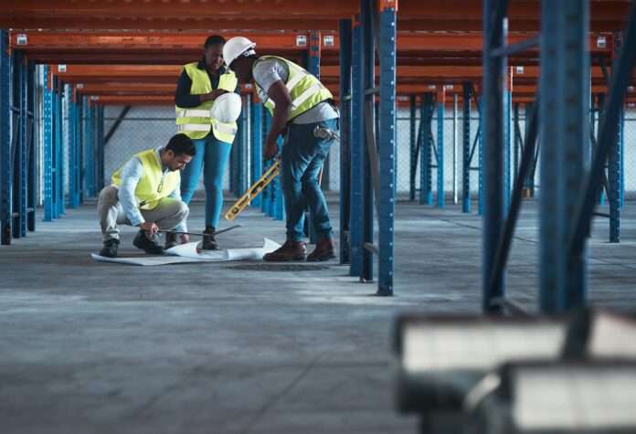 Shot of a group of contractors using a blueprint to plan in the warehouse