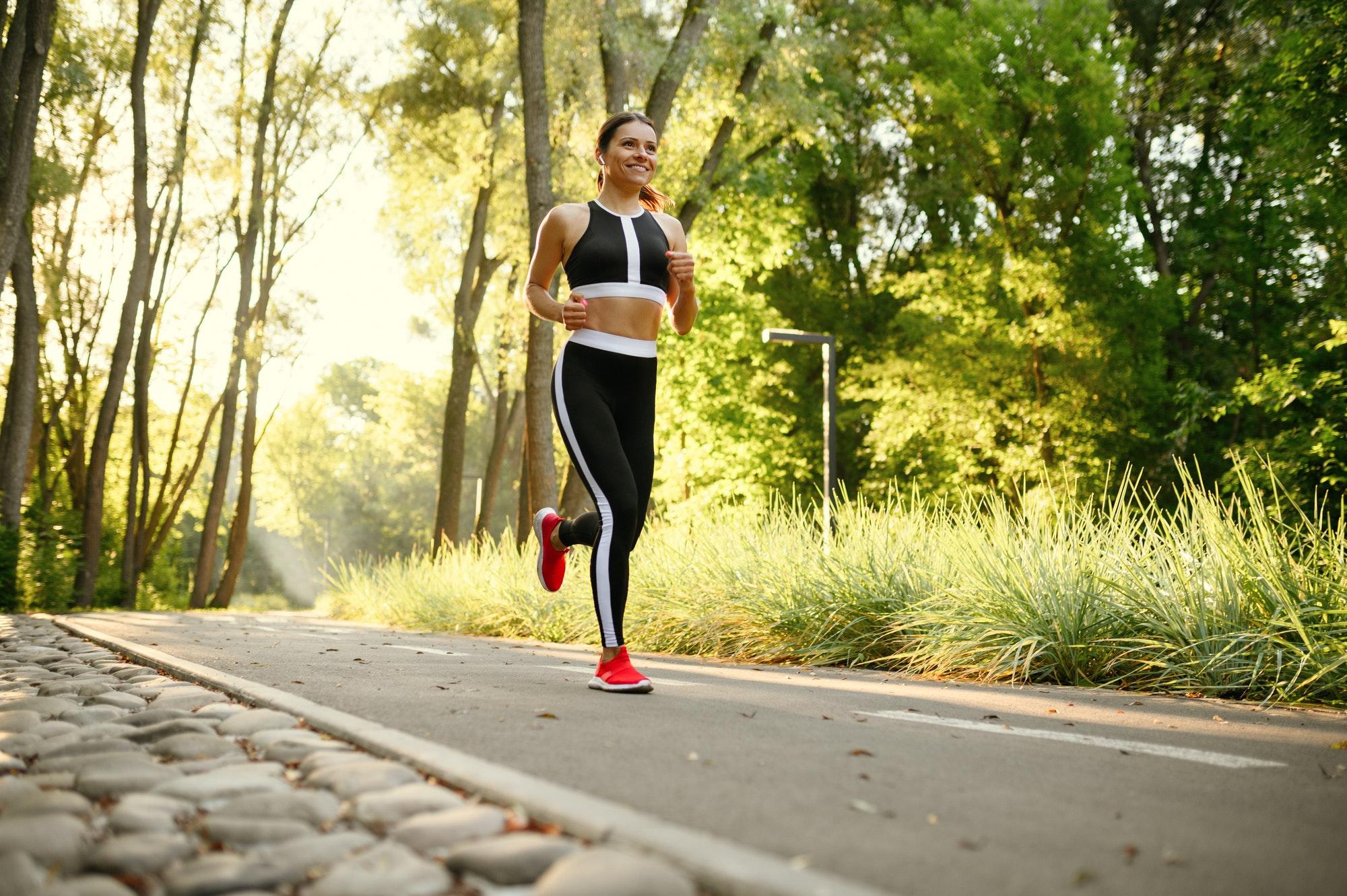Morning training in park, woman running on walkway