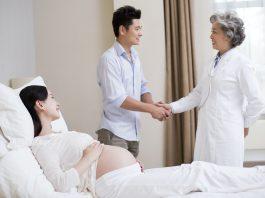 Pregnant woman's husband showing gratitude to doctor