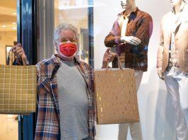 Sale, consumerism and coronavirus concept - senior man wearing mask holding shopping bag