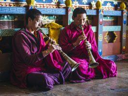 Asian monks playing instruments on temple floor