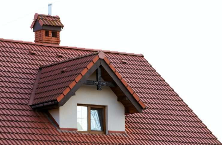 Close up of new orange roof with chimney and small modern window. Concept of modern roof with