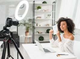 happy african american video blogger in braces holding notebook with influencer marketing lettering