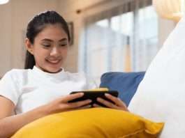 Young happy asian woman watching movie on smartphone