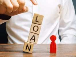 Wooden blocks with the word Loan fall on a miniature person
