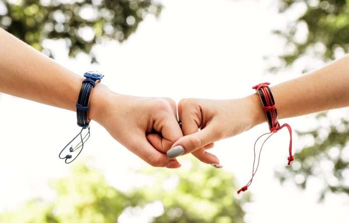 Two female friends showing hands with friendship bracelets