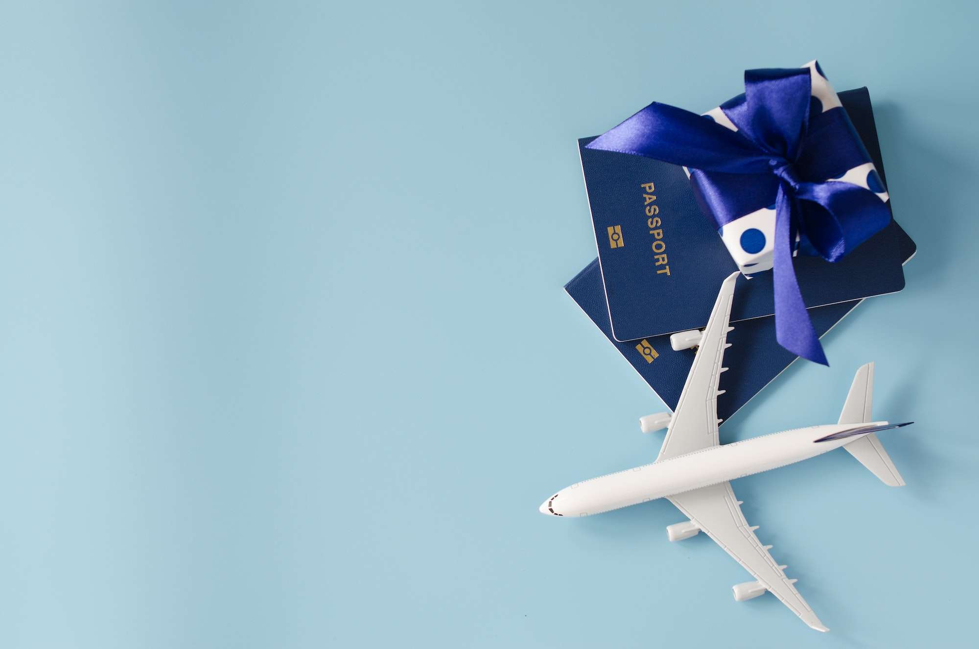 Traveling as gift. Toy airplane with passports and gift box.
