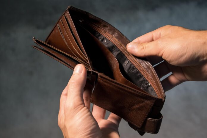 Close-up of hands holding an empty brown wallet, highlighting the impact of daily spending and lack of savings.